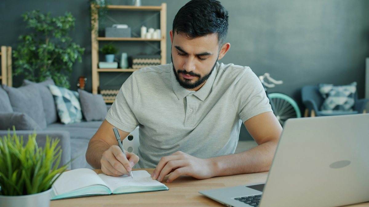 یادداشتبرداری کنار لپتاپ؛ تصویر مرتبط با تدوین هدف تحصیل