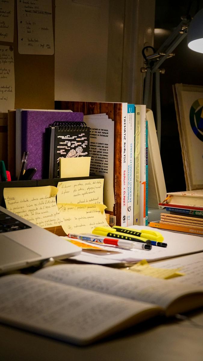 میز مطالعه با کتاب باز، یادداشتها و لپتاپ؛ تصویر مرتبط با آمادگی تحصیلات تکمیلی